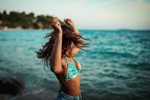 A beautiful young woman is having fun and dancing on the beach. 