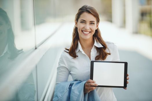 Shot of a young businesswoman holding a digital tablet with empty screen in front of the office building during break.