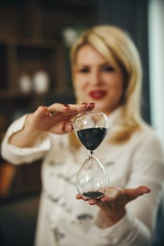 Shot of a beautiful young woman holding hourglass. Selective focus.