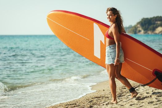 Beautiful young female surfer is preparing for a surf.