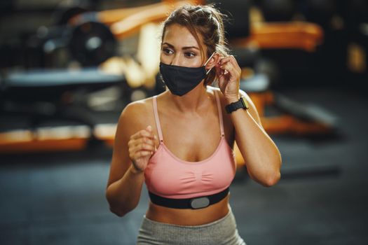 Shot of a muscular young woman with protective mask afther workout during Covid-19 pandemic.