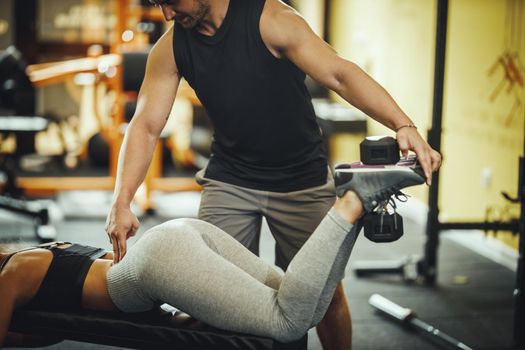 Cropped shot of an attractive young woman working out with personal trainer at the gym.