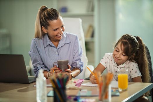 Shot of a beautiful young mother helping her daughter with homework during COVID-19 pandemic.