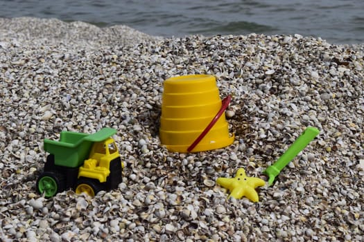Plastic children's toys for sand on the background of the sea. Kids toys. Plastic sand toys. Bright toys. Sand construction. Children's activities. Hobbies and recreation.