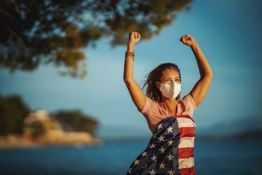 Happy young woman with US national flag and protective N95 mask during preventing the spread of the epidemic and treating coronavirus and pandemic COVID-19.