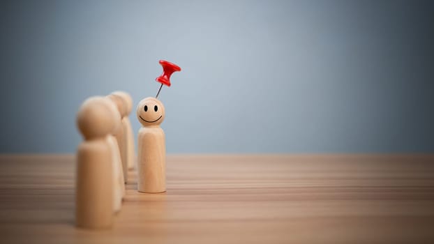 Business and human resources concept for leadership and team leader. A red pin pinned on one wooden doll stands apart and stands out from the crowd.