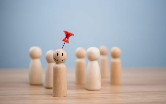 Business and human resources concept for leadership and team leader. A red pin pinned on one wooden doll stands apart and stands out from the crowd.