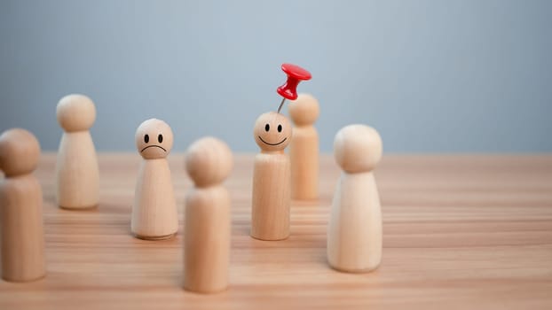 Business and human resources concept for leadership and team leader. A red pin pinned on one wooden doll stands apart and stands out from the crowd.