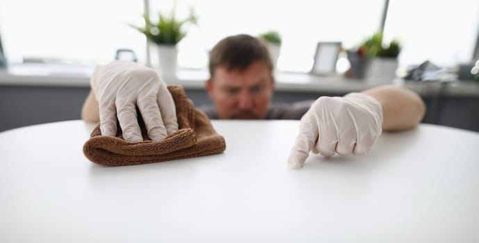 Close-up of cleaning male workers hands swiping dust of company workplace. Serious man wearing white protective gloves. Clean-up service and purity concept