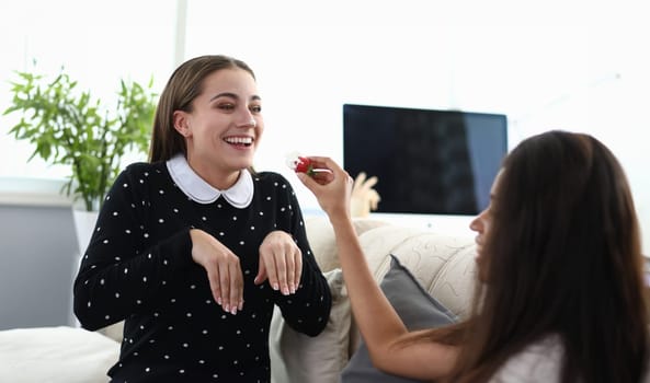 Portrait of cheerful women having fun and playing in game at home. African-american young woman feed girlfriend with juicy strawberry and whipped cream. Friendship or lgbt concept