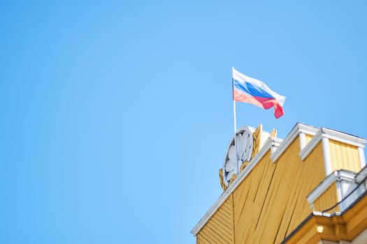 Photo Russian flag against blue sky on yellow wooden gate. Leisure park. State symbols.