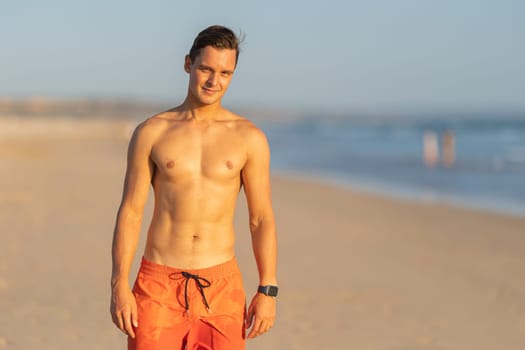 An attractive man with nice athletic body standing on the beach. Mid shot