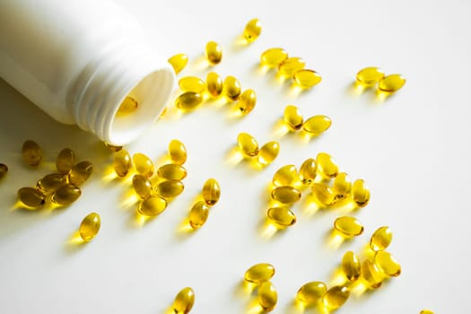 Close up vitamin D3 softgel capsules on a white surface. Yellow softgels, top view, copy space. Nutritional supplements. Health care and immunity support concept
