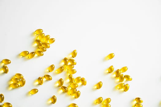 Health care and immunity support concept. Vitamin D3 softgel capsules on a white surface. Yellow softgels, top view, copy space. Nutritional supplements