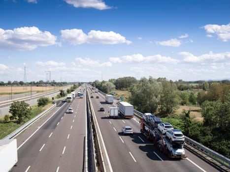 Piacenza, Italy - September 2017 cars and truck on motorway a1 autostrada del sole , daylight, serene sky with clouds.