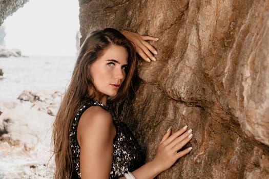 Woman travel sea. Young Happy woman in a long red dress posing on a beach near the sea on background of volcanic rocks, like in Iceland, sharing travel adventure journey