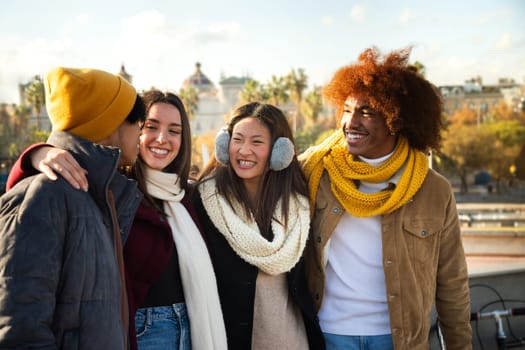 African American man enjoying sunny winter afternoon with multiracial group of friends. Young happy people embracing having fun outdoors. Lifestyle concept.