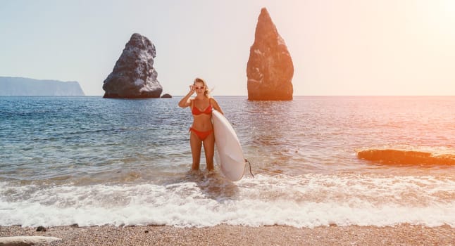 Close up shot of beautiful young caucasian woman with black hair and freckles looking at camera and smiling. Cute woman portrait in a pink bikini posing on a volcanic rock high above the sea