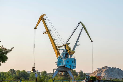 Harbour cranes are loading sand and gravel on a barge. Loading materials by crane.