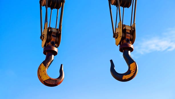 A close-up of a gantry crane hook against a blue sky.