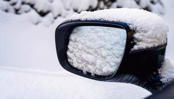 side window of car in the snow. Closeup shot of a car side mirror covered with snow on white snowy ground