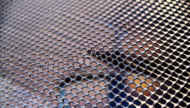 steel cladding of a building with a expanded metal lattice structure. galvanized gray nets protect the industrial building. Blue sky in contrast to a silver background, wall