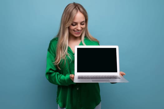 a cute girl demonstrates a laptop with a screen to insert a page on a blue bright background.