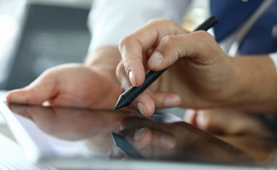 Close-up of male hand signing agreement on modern tablet. Manager and client discussing condition of contract. Business company and negotiations concept