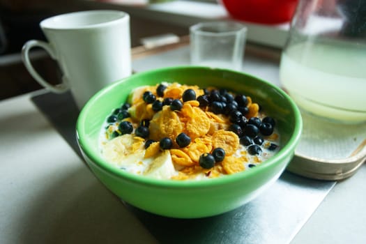 Close up of a bowl of cornflakes with blueberries and banana in milk