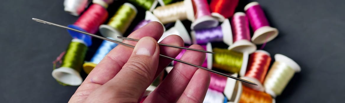 classic sewing needle and threads in a tailor's hand,sewing needle close-up,