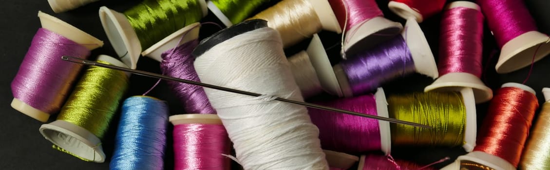 close-up there are lots of colorful spools of thread, thick sewing thread, big needle,