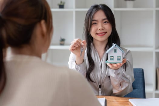 real estate agent or banker handing over a key to their customer after signing a contract.