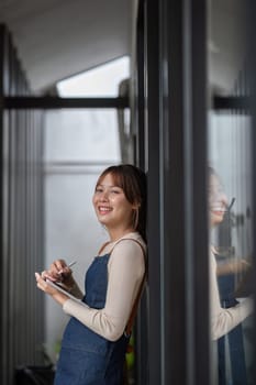 Asian coffee shop owner or barista smiling at coffee shop and holding tablet Female small business owner in food and beverage.