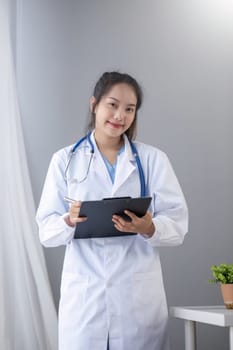 Portrait of female doctor wearing white coat with stethoscope holding clipboard and looking confidently to camera.