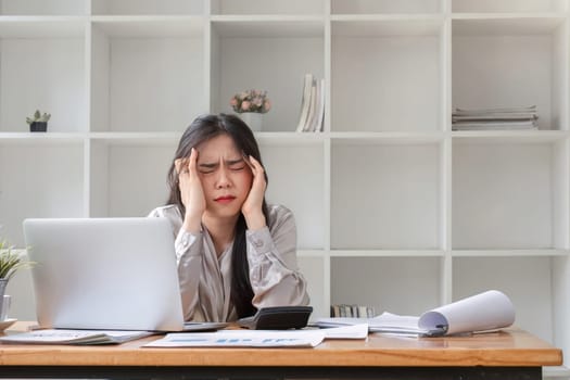 businesswoman looking stressed out while working in an office. Stressed business woman working from on laptop looking worried, tired and overwhelmed.