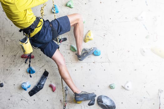 Close up view of young man or climber feet in climbing shoes on artificial indoor wall at a climbing center, sport activity concept