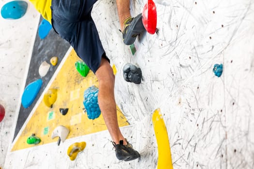 Close up view of young man or climber feet in climbing shoes on artificial indoor wall at the climbing center, sport activity concept