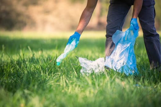 Man picking up plastic bottle, garbage collecting in forest cleaning planet, help garbage collection charity environment, garbage in a forest