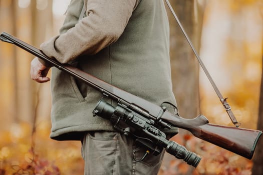 Hunter or ranger with gun or rifle in a forest hunting of some venison, hunting period, autumn season, hunting and people concept