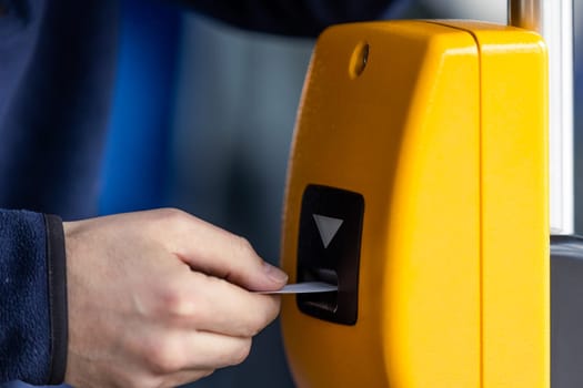 Young man hand inserts the bus ticket into a validator, validating and ticking