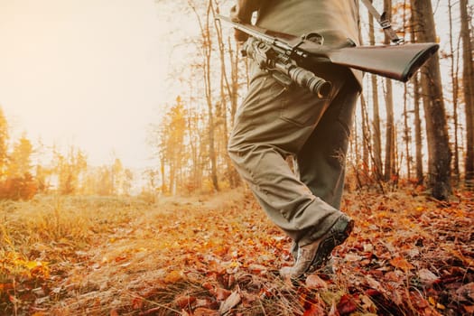 Autumn hunting season, hunter with rifle looking out for some wild animal in the wood or forest, outdoor sports concept