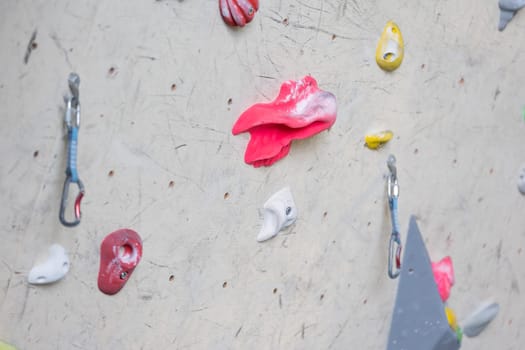 Close up of colorful hooks or grips with carbines for climbing wall