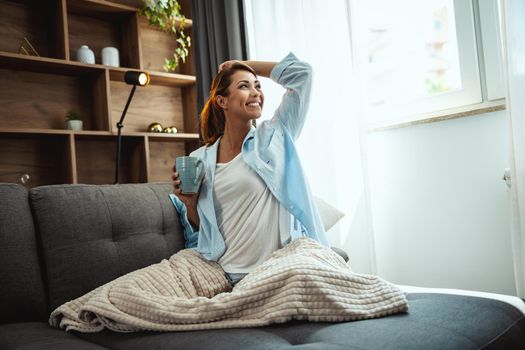 Shot of an beautiful young woman sitting on the sofa and enjoying a cup of coffee at home.