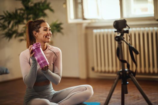 Young beautiful sporty woman vlogger is making video training for blog about healthy living and exercises in front of a camera at home. 