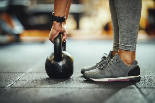 Cropped shot of a unrecognizable female athlete working out with kettlebell at the gym.