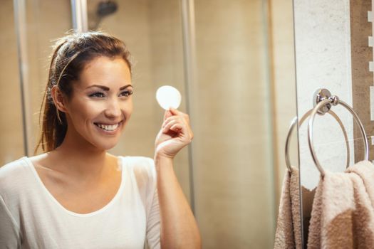 Shot of an attractive young woman about to wiping her face with a cotton pad in the bathroom at home.