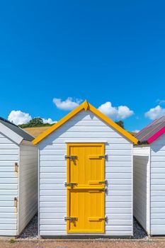 Colourful beach houses. Row of multicolored beach huts against blue sky.