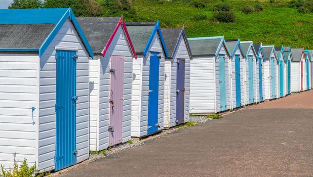 Colourful beach houses. Row of multicolored beach huts against blue sky.