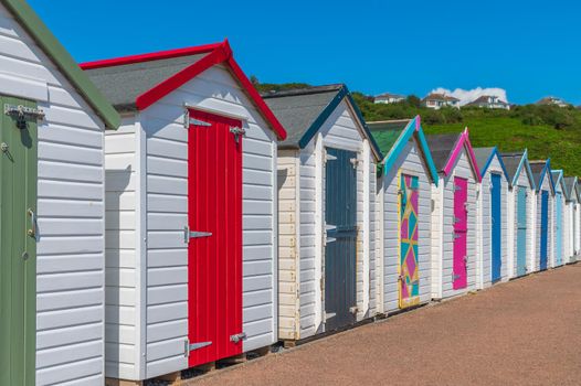 Colourful beach houses. Row of multicolored beach huts against blue sky.