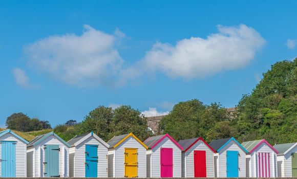 Colourful beach houses. Row of multicolored beach huts against blue sky.